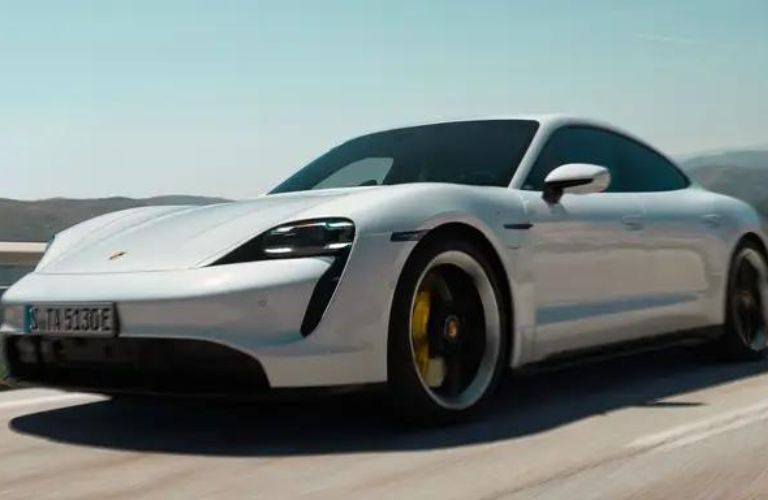 One white color 2024 Porsche Taycan is running on the road.