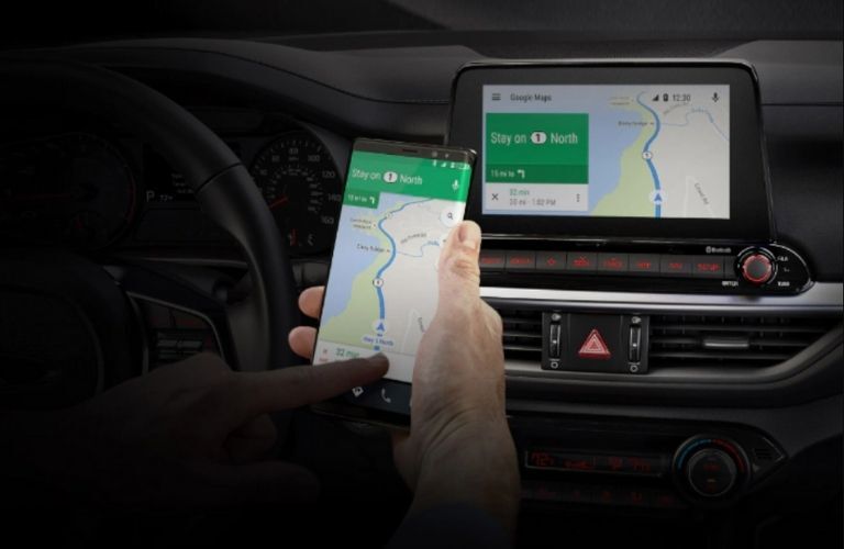 driver accessing the available navigation system of the 2021 Kia Forte