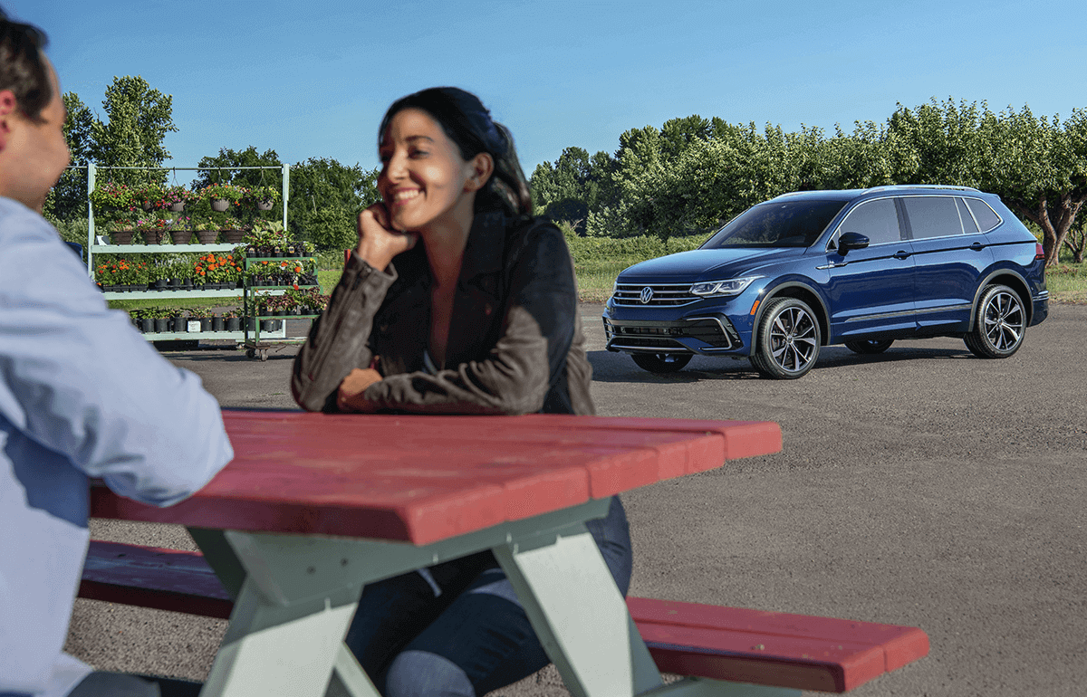 An Atlas is parked with a family enjoying time outside in the background.