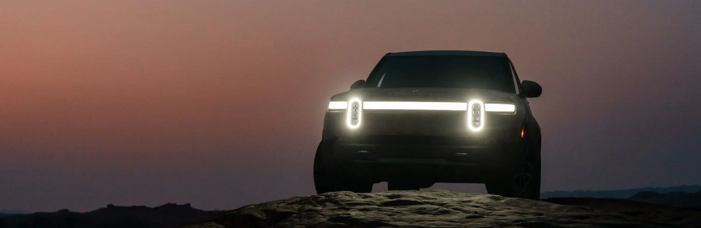 2022 Rivian R1T parked off-road with lights on