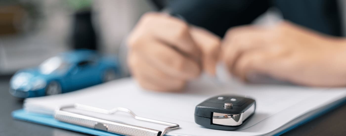 A car salesman is filling out paperwork at a dealership.