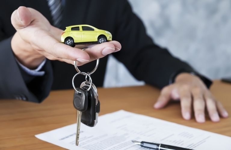 A toy car model and keys in a man's hand