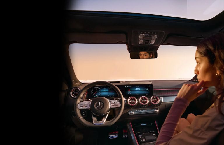 A woman looking in front with the front dash of the Mercedes-Benz vehicle on display