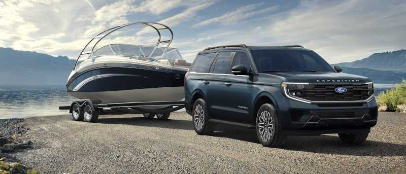 A front quarter view of the 2027 Ford Expedition towing a large lake boat