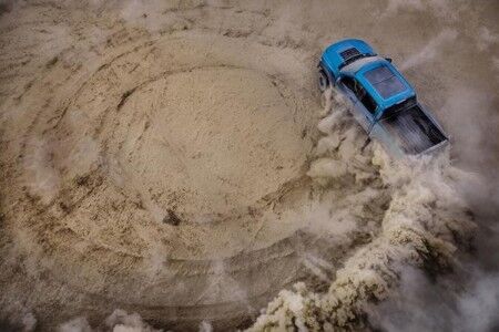 Overhead view of blue 2019 Ford F-150 Raptor spinning through sand