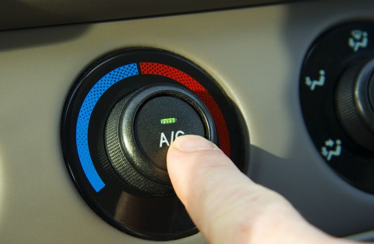 close up of a finger pushing the A/C button in a car
