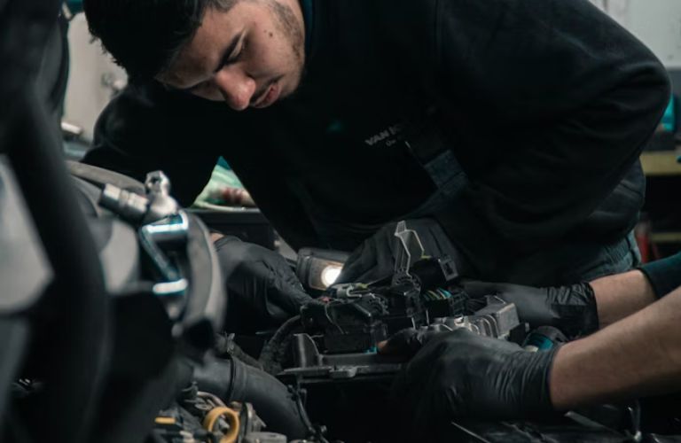 Technician checking under the hood of the vehicle