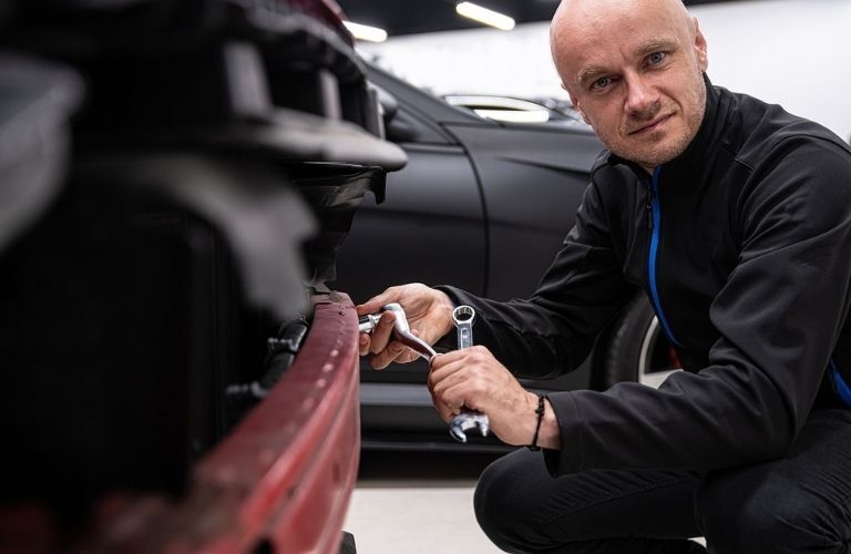 mechanic checking the bumper of a car