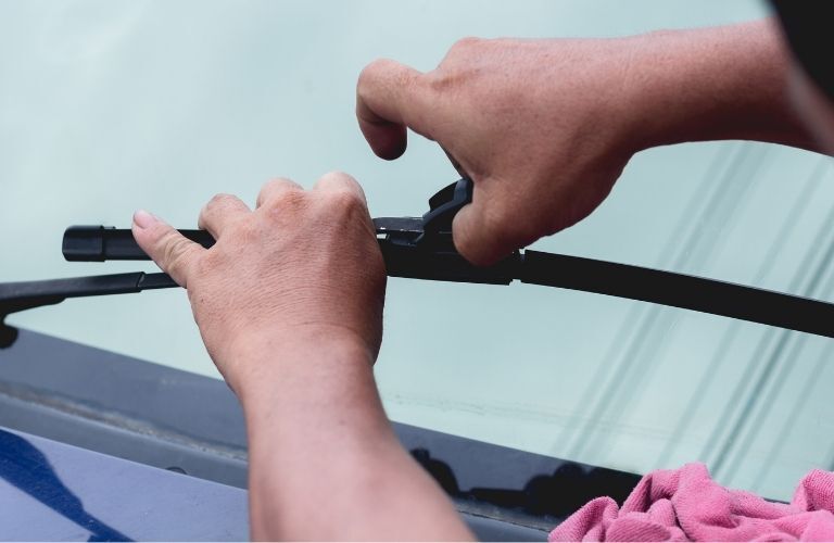 Hands of a mechanic working on windshield wiper
