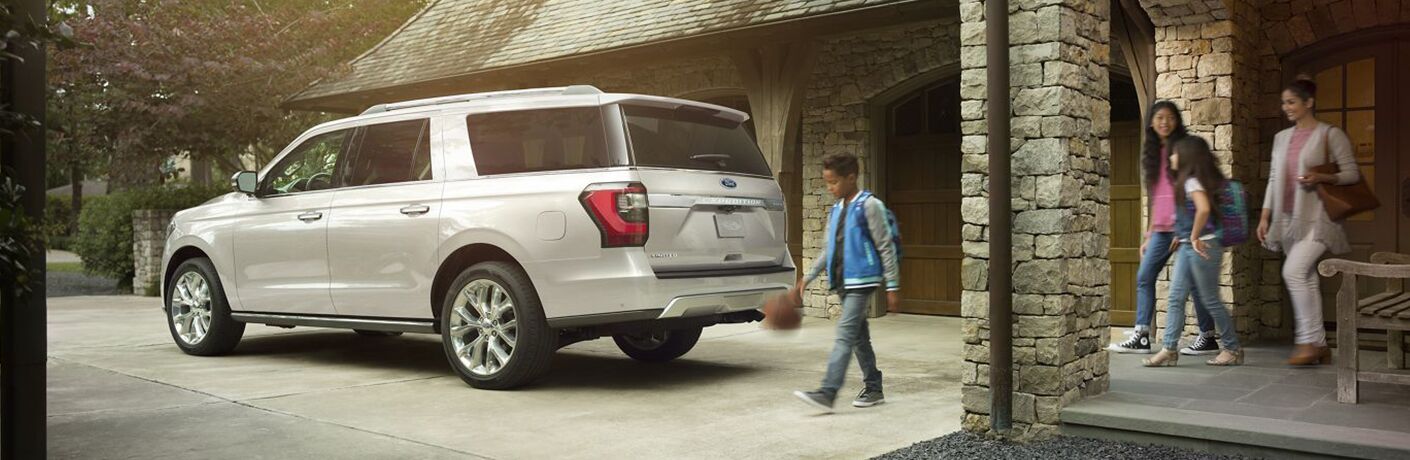 Three people walking towards white Ford Expedition