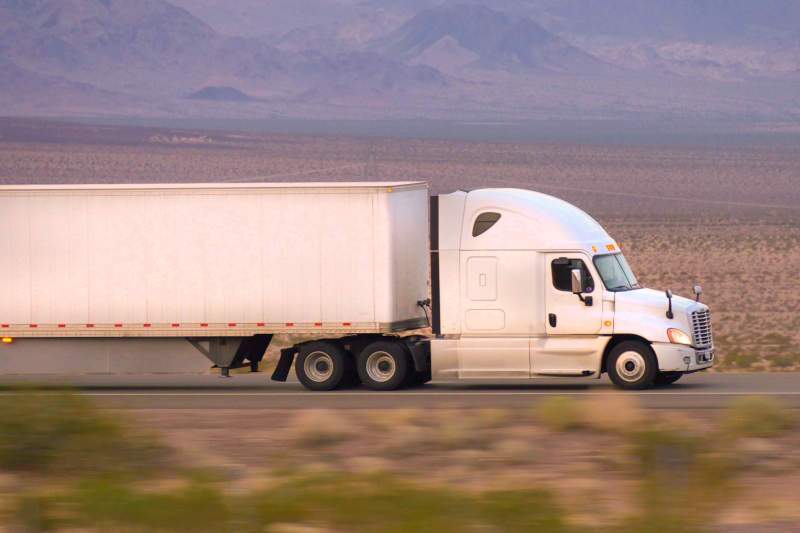 A large semi truck driving along a desert highway.