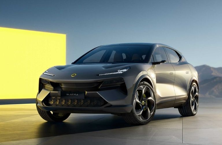 Front view of a grey 2023 Lotus Eletre all-electric hyper SUV parked outdoors in front of a yellow screen