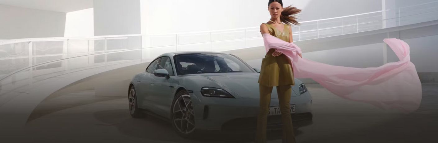 a woman standing in front of a 2026 Porsche Taycan
