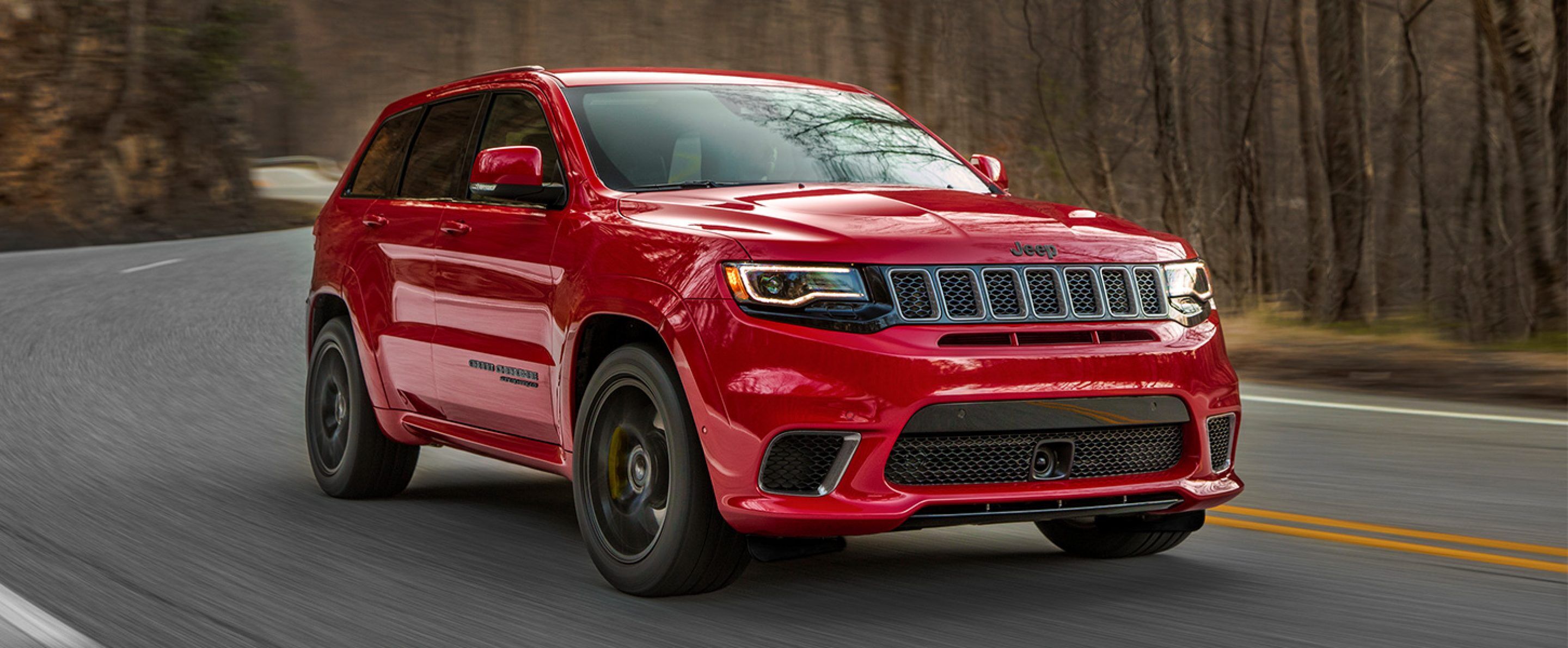Red 2021 Jeep Grand Cherokee driving on a winding road