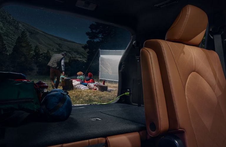 People watching a movie by connecting a screen to the 120V/1500-Watt Power Outlet of the  2024 Toyota Highlander Hybrid