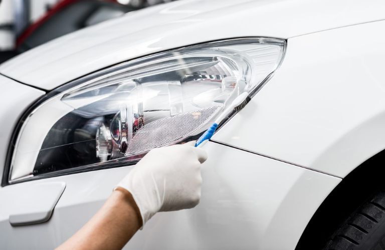 technician cleaning the headlight with a tool