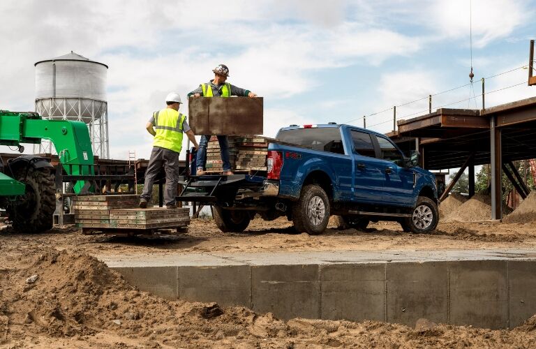 Workers loading cargo in rear area of blue 2020 Ford Super Duty
