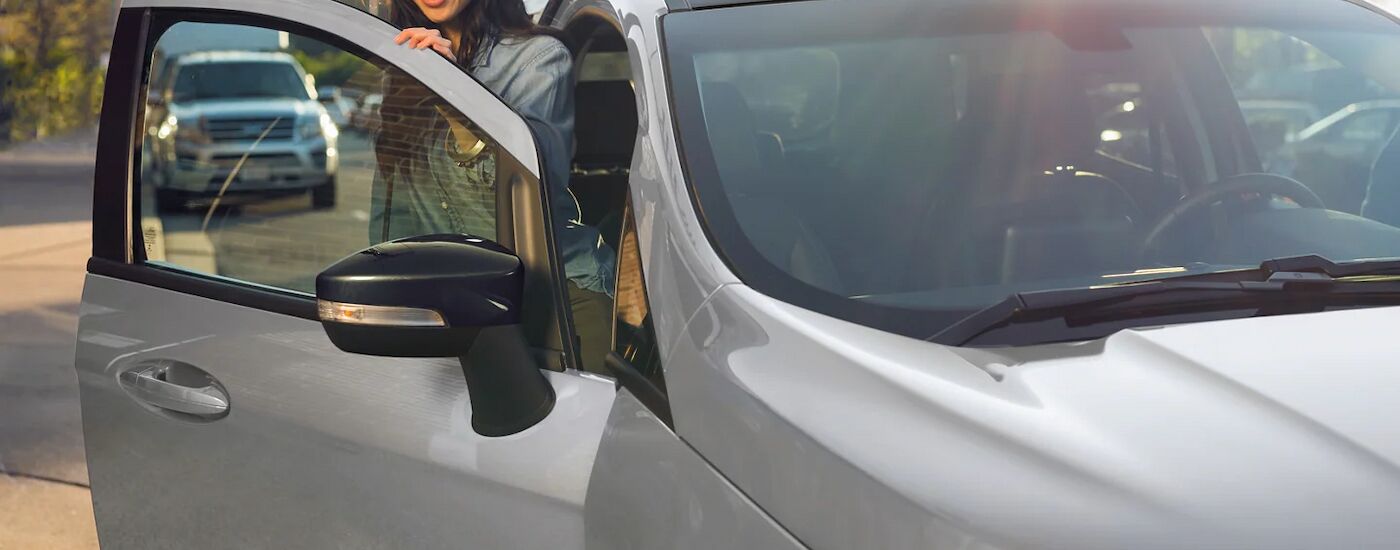A woman is getting out of the passenger side of a grey 2022 Ford EcoSport.