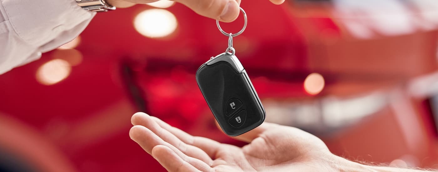 A close up of a car key being handed to a customer.
