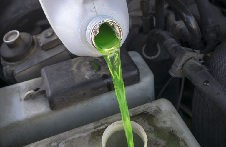 A green colored antifreeze being poured into an engine