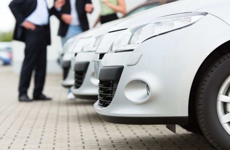 close up of silver car hoods with people in the background