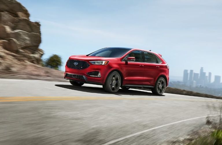 red 2024 Ford Edge driving on a road away from a city