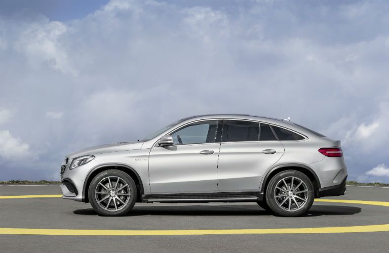 2020 MB GLE Coupe exterior driver side profile in empty lot with fluffy clouds in sky