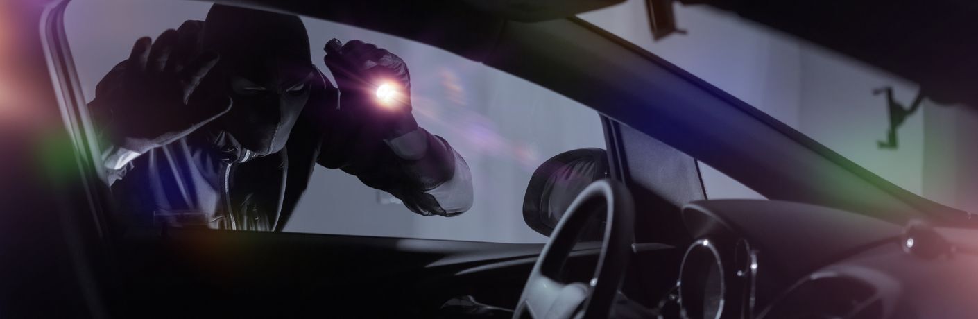 Representative image of a robber checking out a car with a torch