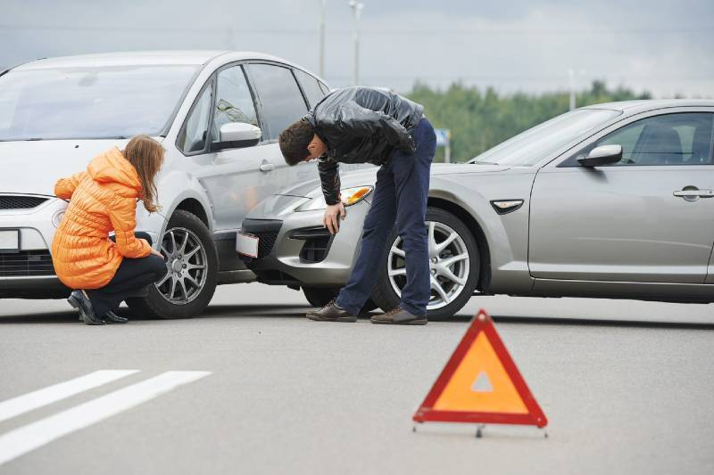 A fender bender between two cars, with a man and a woman examining the damage