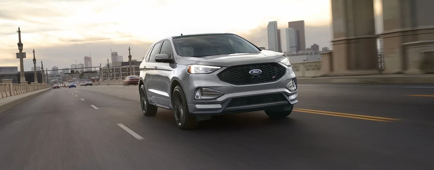 Silver 2023 Ford Edge, a used SUV for sale near North Bergen, driving on a highway.