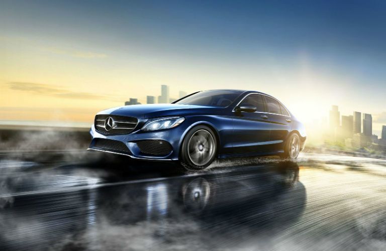 blue Mercedes-Benz C-Class driving on wet road outside city