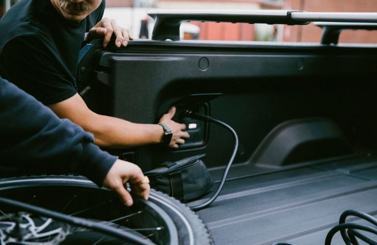 two men checking the charging point of a pre-owned Rivian