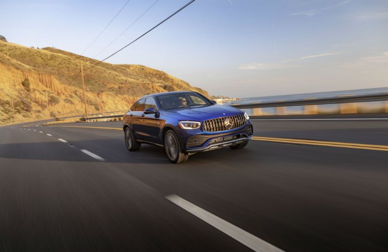 2020 MB GLC Coupe exterior front fascia passenger side on highway in front of hill and lake