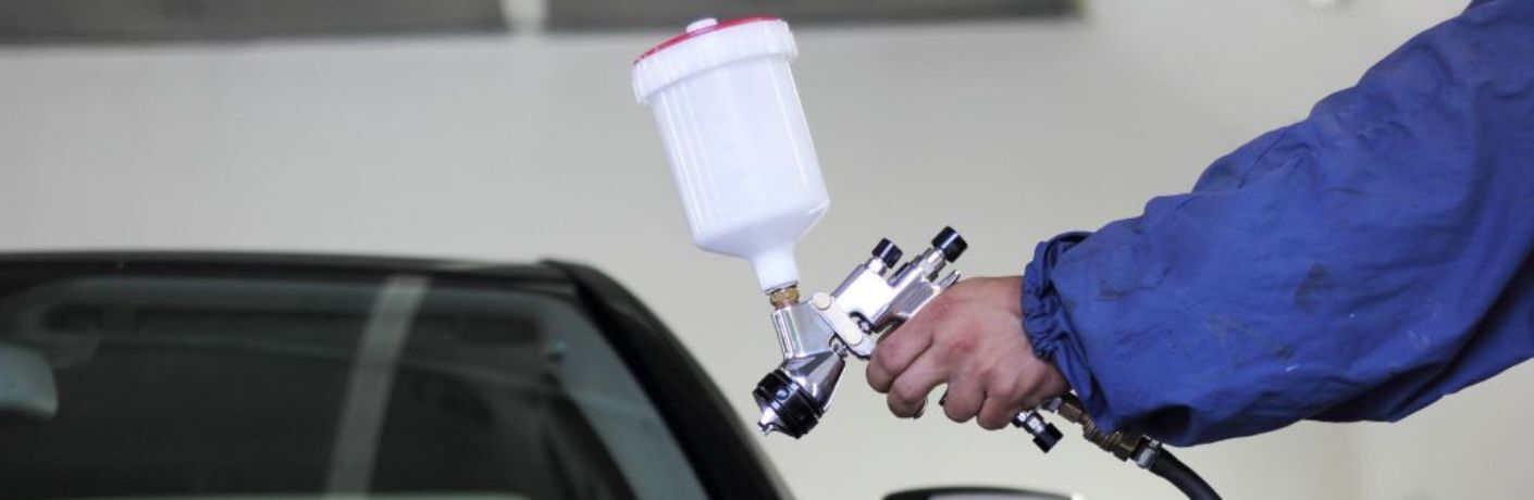Technician powder coating a vehicle