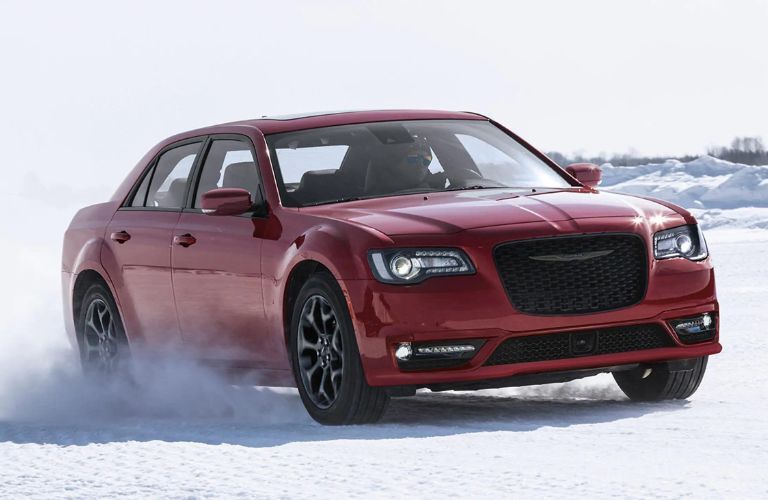 One red color 2022 Chrysler 300 is running on snow-laden road.