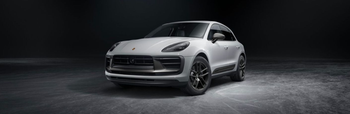 Front quarter view of a white 2023 Porsche Macan T parked in a dark room