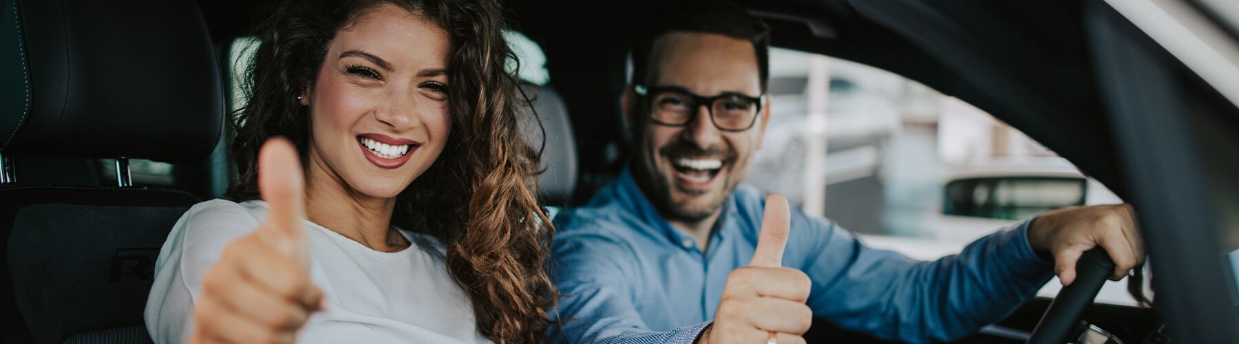 two happy people in their new car