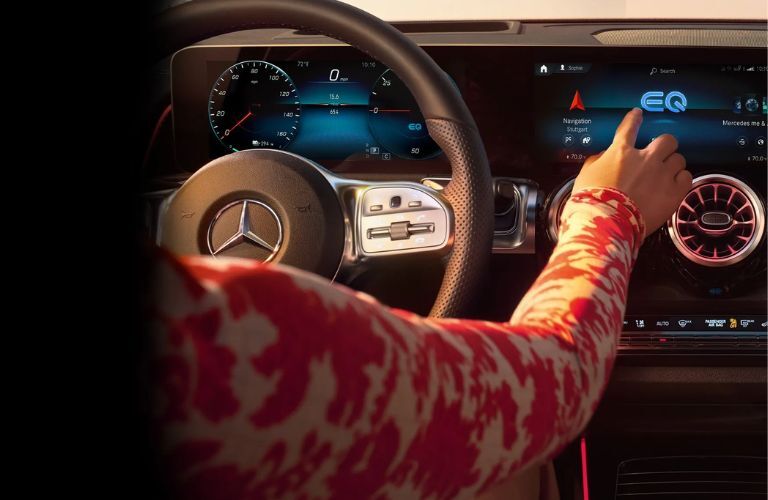 Hnads of a woman touching the Mercedes-Benz display and drivingAdaptive Cruise Control