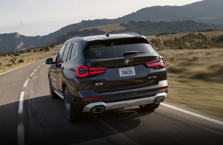 Rear view of the 2023 BMW X3 driving on road