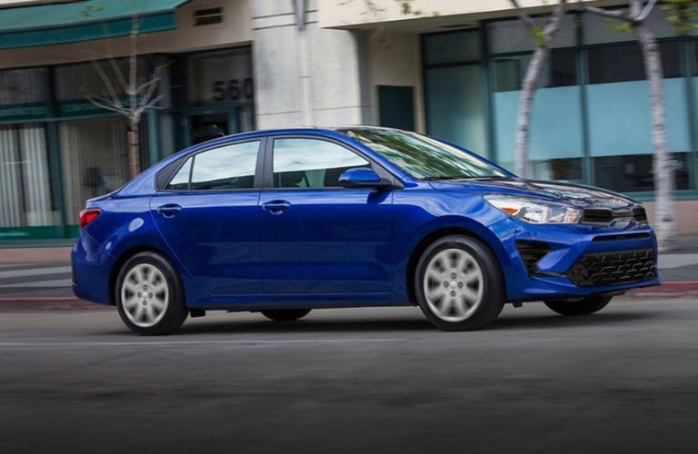 2023 Kia Rio Driving Down a City Street Side View