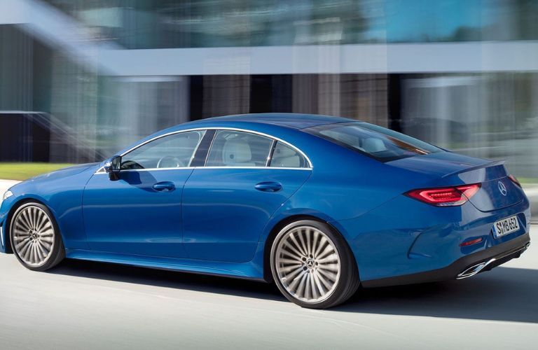 Side view of a blue 2022 Mercedes-Benz CLS Coupe driving on a road.