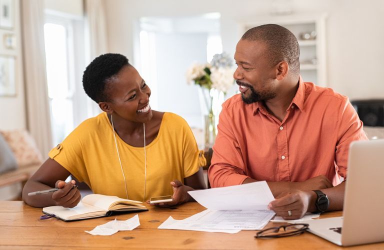 A smiling couple with papers on hand