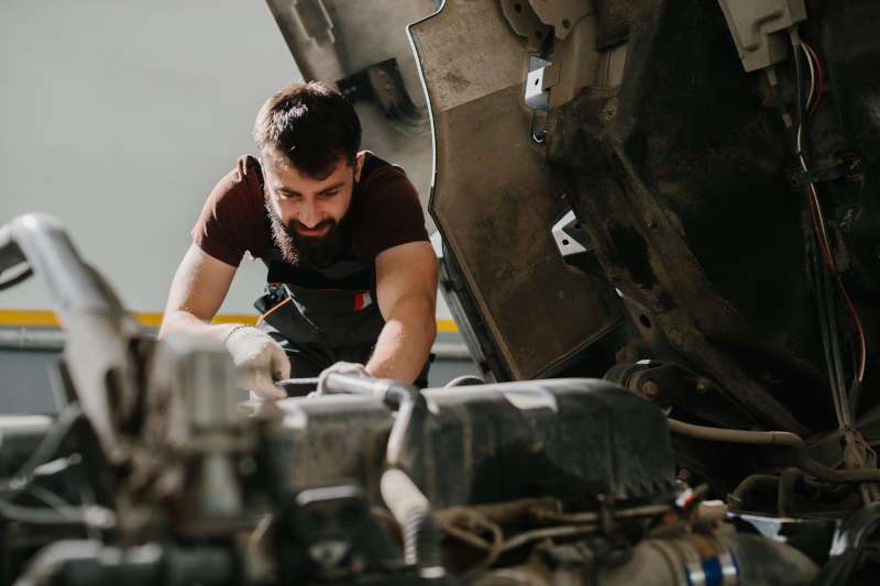 A man performing engine service on a commercial truck