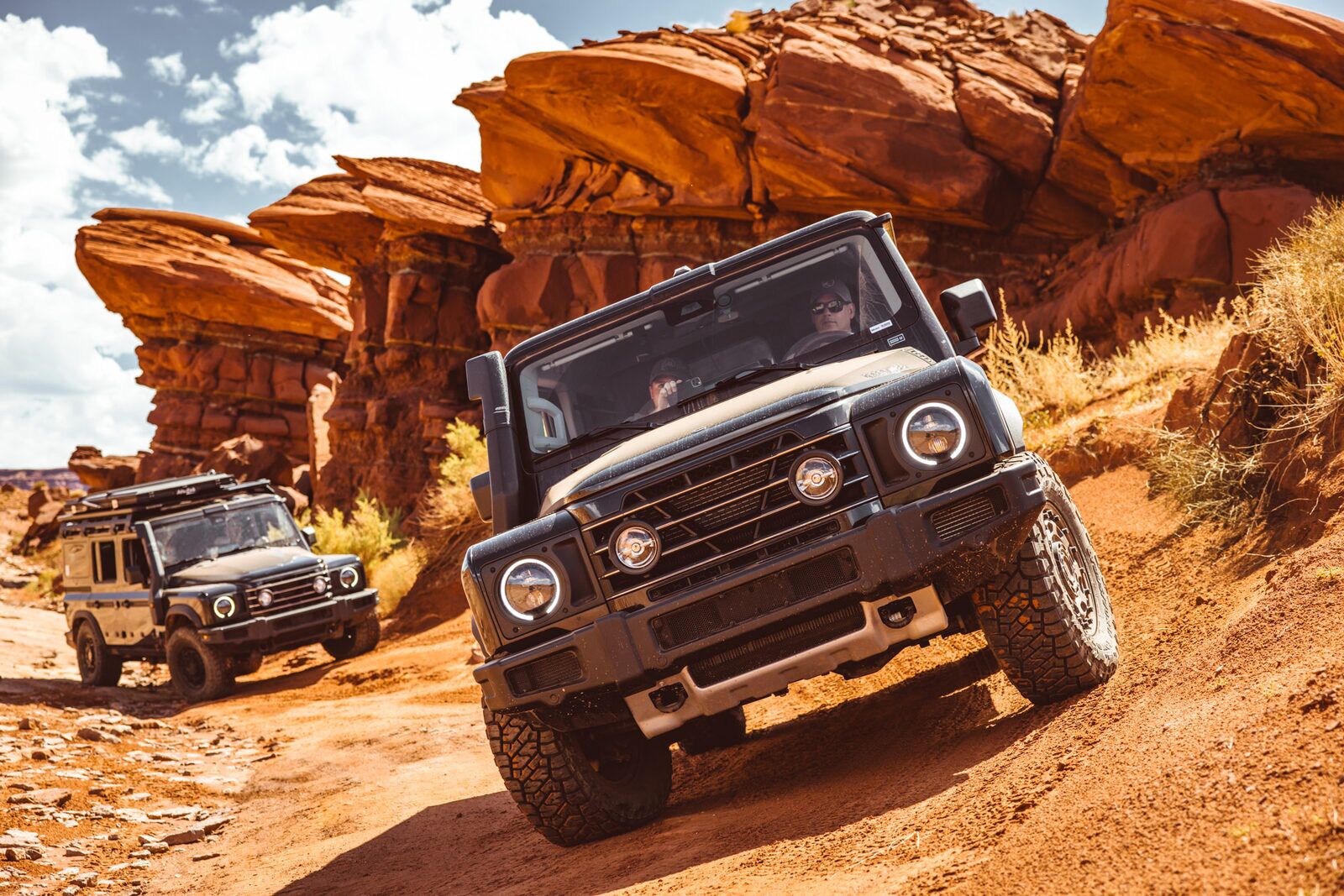 Two Grenadiers climbing a steep red-rock trail beneath sandstone cliffs on a Hard Way Home run near Moab