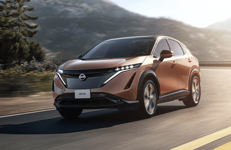 One brown color Nissan Ariya is running on the road.