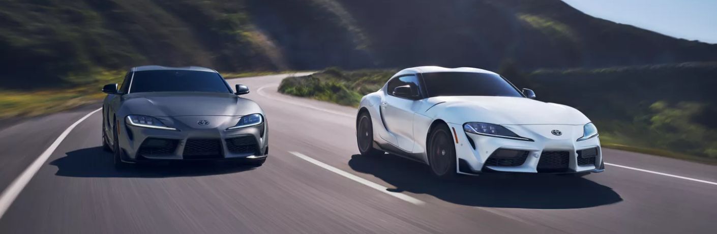 Two 2023 Toyota GR Supra models speeding on a road