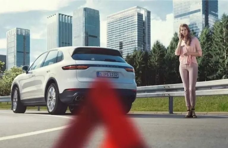 Image showing a woman making a phone call standing behind a white Porsche Macan SUV
