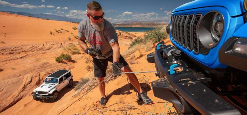 A man using the front-mounted winch on the 2025 Jeep Wrangler.