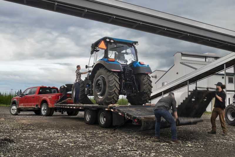 A Ford Powerstroke equipped truck pulling a large trailer with a tractor on it