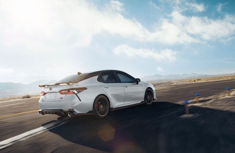 2021 Toyota Camry white with spoiler driving around curved road